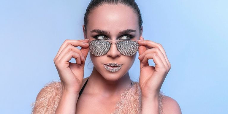 Primer plano de una mujer con gafas de sol de pedrería y labios de pedrería