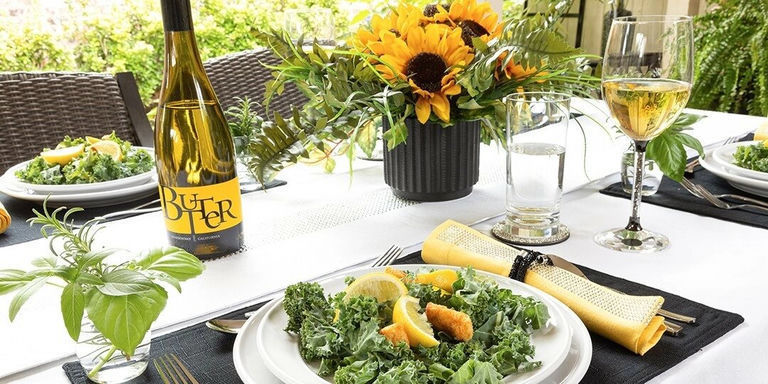 Décor de table printanier avec tournesols, verdure et accents jaunes sur une nappe blanche