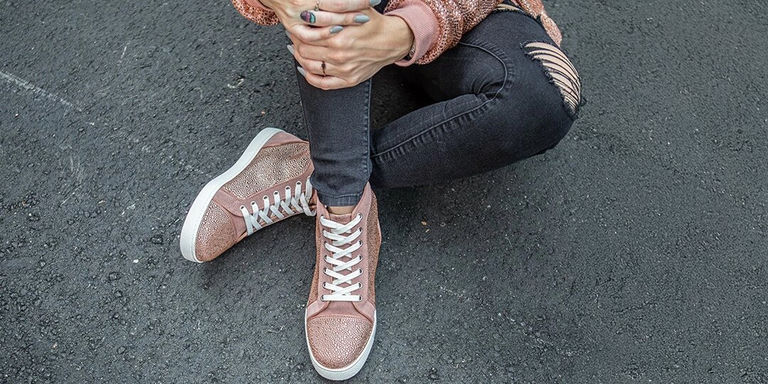 Primer plano de zapatillas cubiertas de pedrería rosa combinadas con jeans negros desgastados para un estilo urbano