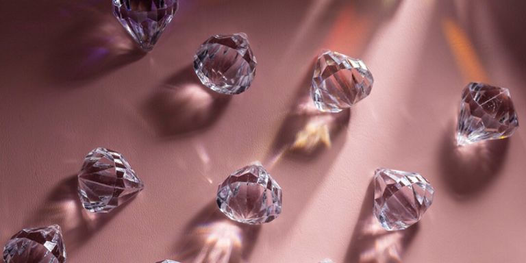 Clear crystal rhinestones catching light on a pink background