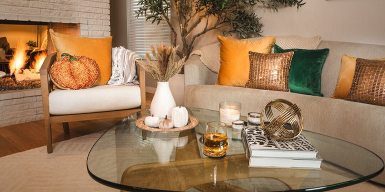 configuration de salon glamour et confortable avec coussins en strass, accents citrouille et table basse en verre