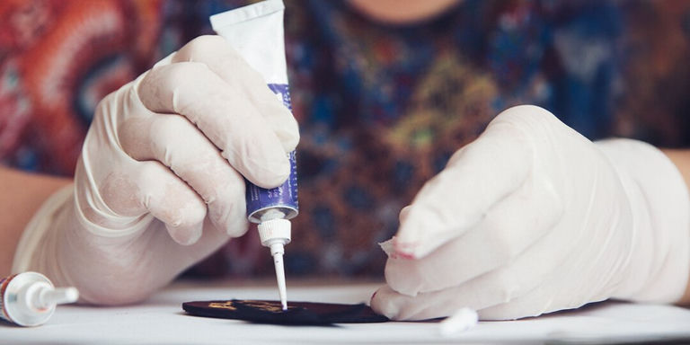 Person wearing gloves applying glue to a leotard with precision for rhinestone application