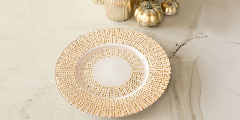 assiette de présentation dorée à clous stylisée avec une décoration d’automne glamour sur un plan de travail en marbre