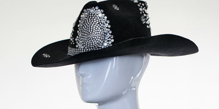 Black felt cowboy hat covered in large circular rhinestone embellishments on a mannequin head