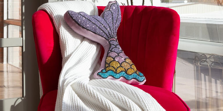 Coussin rose vif en forme de queue de sirène en strass stylisé sur canapé moderne neutre