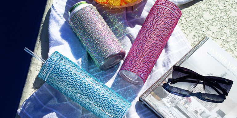 Gobelets scintillants en strass et glacière à canettes à côté de lunettes de soleil et serviette de piscine