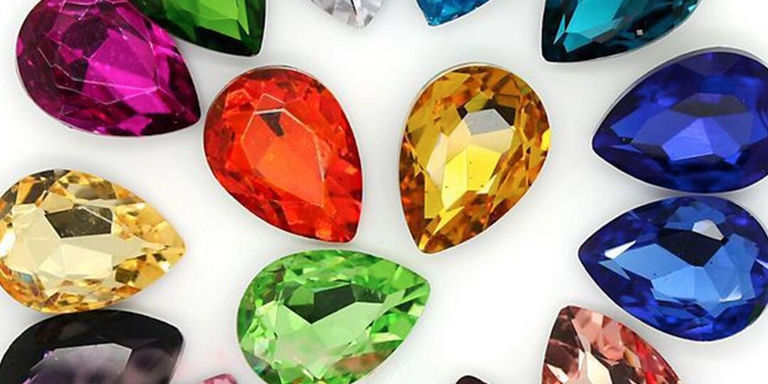 Surtido de diamantes de imitación coloridos en forma de lágrima exhibidos sobre un fondo blanco