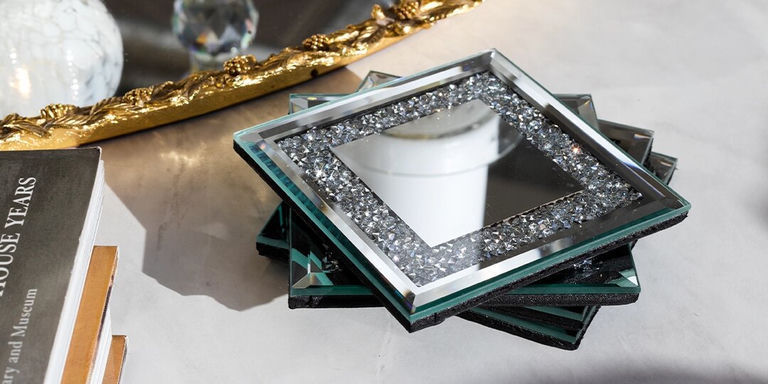 square mirrored coasters with rhinestone borders on marble surface