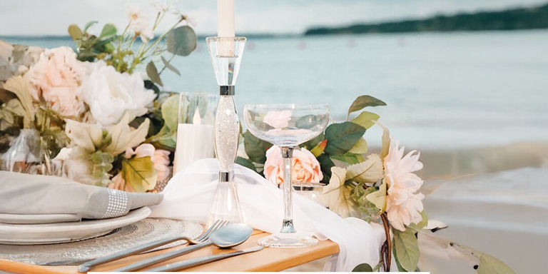 Coupe de champagne glamour et lumière de bougie sur chargeur en strass au coucher du soleil sur la plage