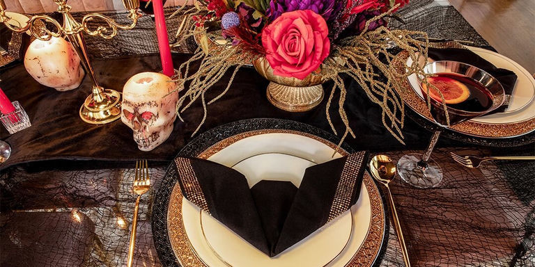 decoración de mesa de Halloween en negro y dorado con flores dramáticas y luz de velas
