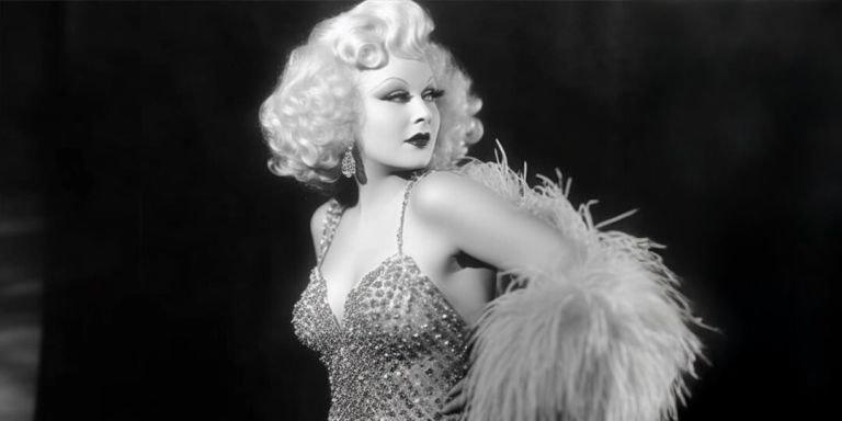 Retrato vintage de una mujer glamorosa con un vestido adornado con pedrería y una boa de plumas en blanco y negro