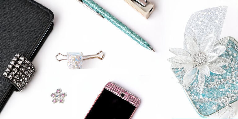 Flatlay of rhinestone-decorated office supplies and accessories including pen, phone case, and clips